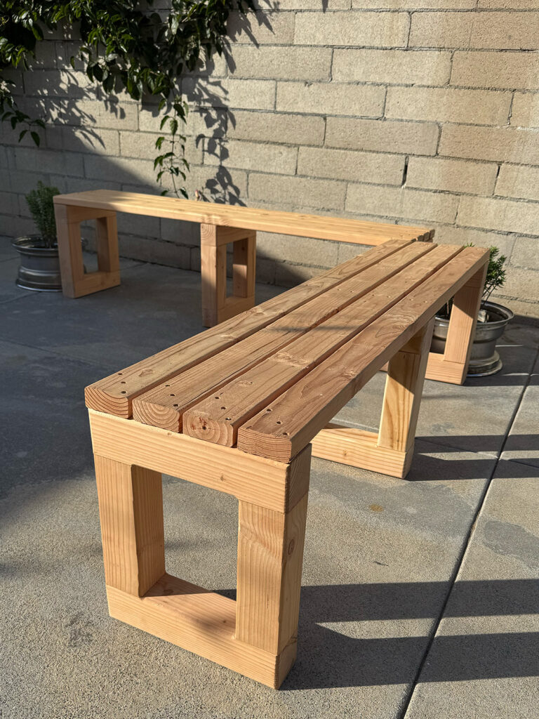 Two L-shaped benches forming a corner seating arrangement in a outdoor setting.