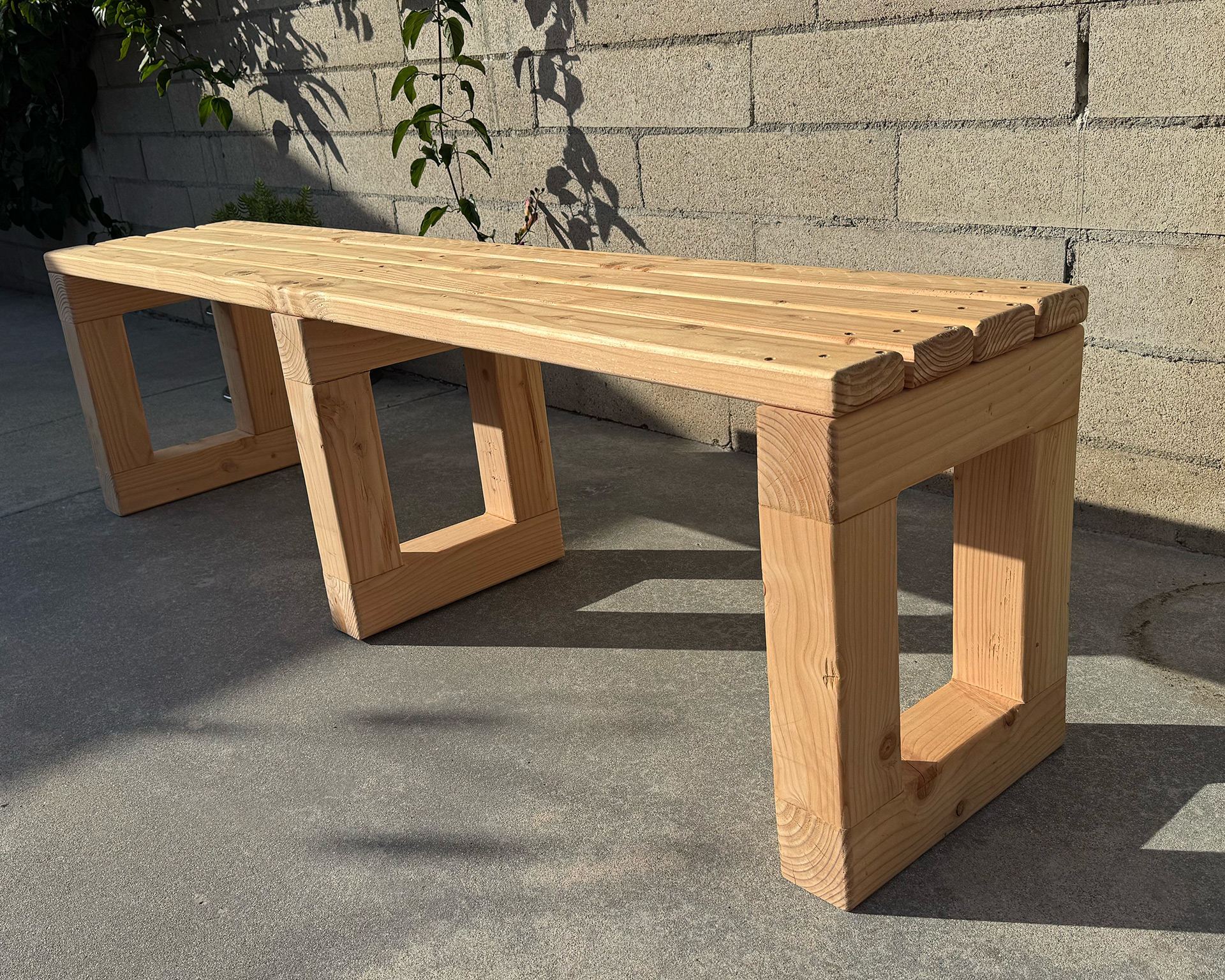 Side, close-up angle of a modern 2x4 wood bench showing wood grain and construction.